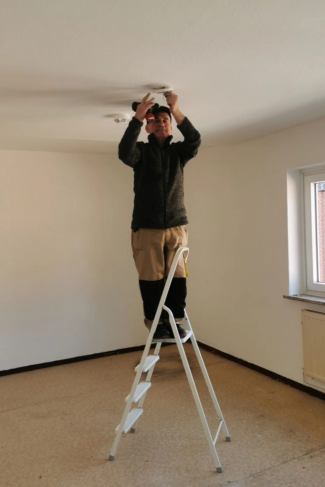 Fitting a ceiling detector from a step ladder, for ceiling fan installation in Calgary