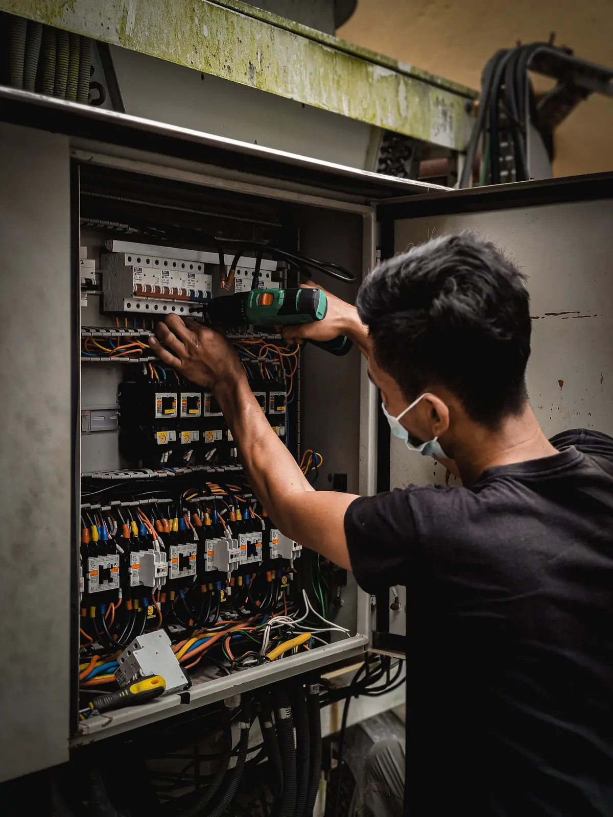 An electrician working inside a large distribution board, for commercial electrical in Calgary