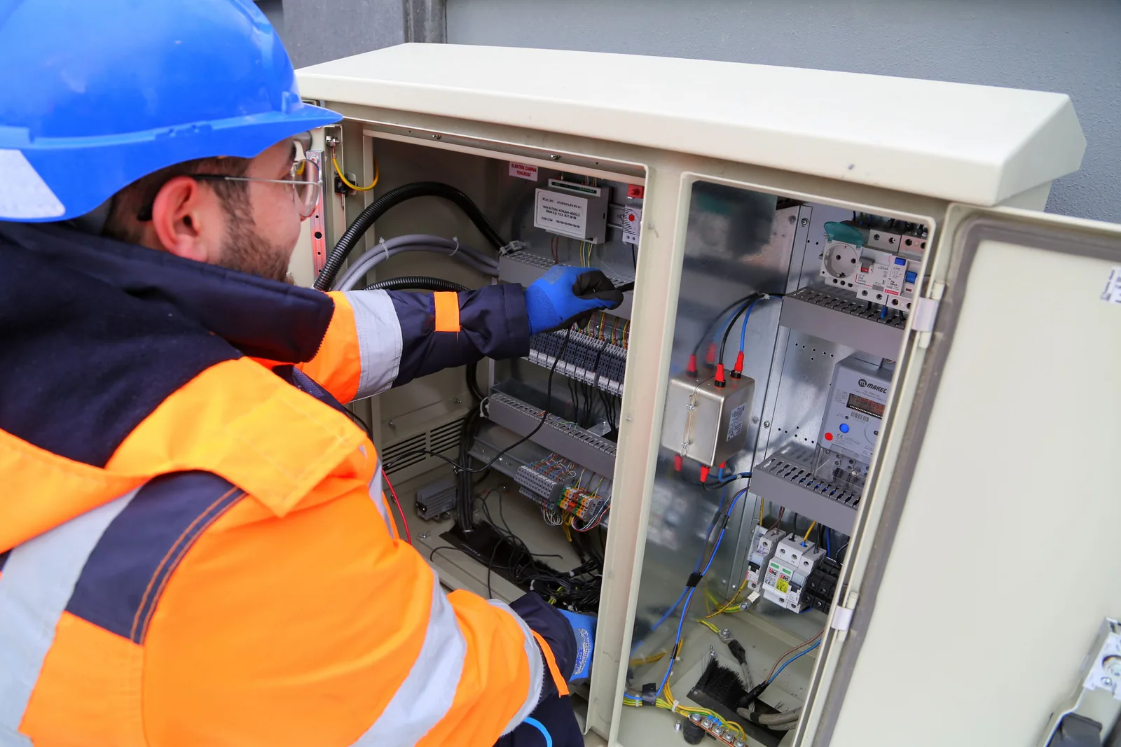 An electrician working in an outdoor service cabinet, for maintenance plans in Calgary